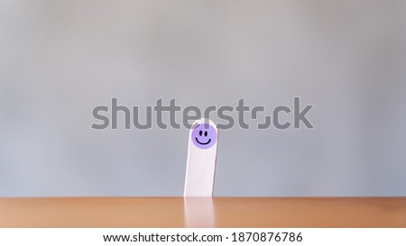A hand draw happy emotion face on wooden stick with background