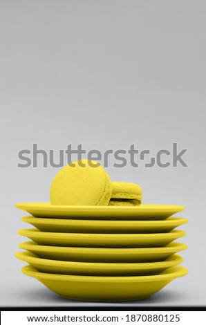 Yellow macaroons with plates on a gray background. Fashionable color combination.