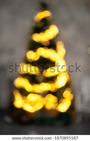 Demonstrating trendy colors of year 2021 - Gray and Yellow. Defocused background of shiny coniferous tree with light garlands at Christmas night