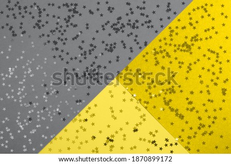 Beautiful festive abstract yellow gray background withmetallic star shaped confetti. Holidays background. Color trend 2021.