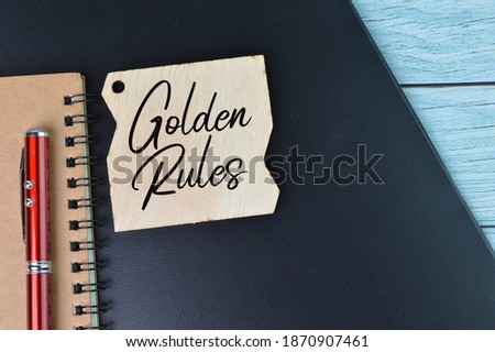 Top view of black file, notebook, pen and wooden board tag written with text GOLDEN RULES. Business concept.