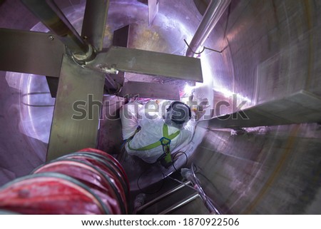 Welding  arc argon worker male repaired metal is part tank stainless construction inside confined space