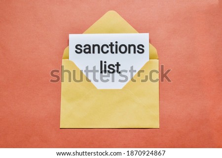 Sanctions list. Envelope that says SANCTIONS LIST  on a pink table. Flat lay. Business and finance concept.