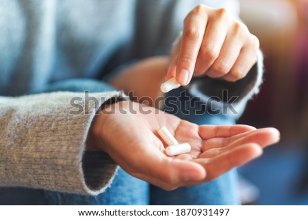 Closeup image of a woman holding and picking white medicine capsules in hand Royalty-Free Stock Photo #1870931497