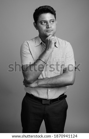 Portrait of young Indian businessman against gray background