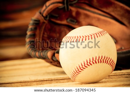 Baseball - This is a shot of an old worn baseball sitting in front of an old glove. Shot in a warm retro color tone with a shallow depth of field.