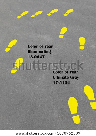Yellow positive footprint or foot steps on gray asphalt. Color trend 2021