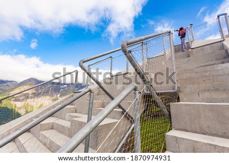 Woman photographer with camera and norwegian flag on Utsikten viewpoint at Gaularfjellet. Tourist attraction. Scenic route in Norway.