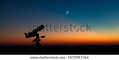Silhouette of a astronomy telescope with twilight sky. Royalty-Free Stock Photo #1870987366