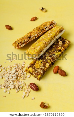 Vertical image.Delicious crunchy diet bars, nuts, oatmeal on the bright yellow background