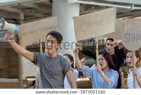 Focus on male leader of protestors shouting out for human rights with signs