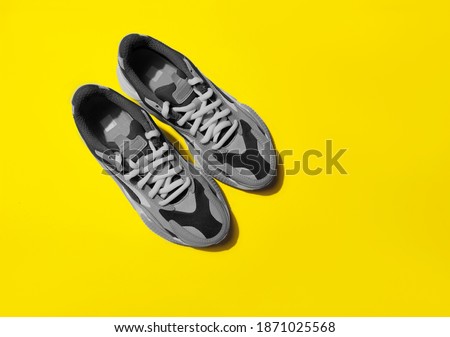 Illuminating and Ultimate gray Pantone color of the year 2021 sport shoes on yellow background with shadows
