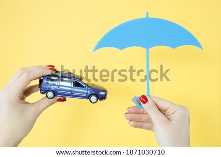 They are holding a car and an umbrella. Vehicle insurance concept
