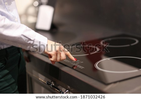 Female finger presses button on touch electric stove. Sale of household appliances koncetp Royalty-Free Stock Photo #1871032426