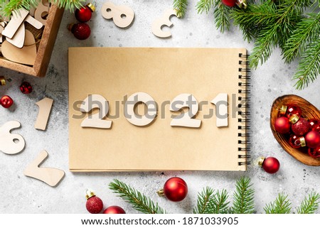Happy New Year to 2021. The number 2021 is written in Notepad. Christmas background with fir branches is decorated with the symbol of  bull cow made of wood. Top view