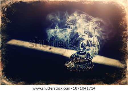 incense in a woman hand, incense smoke on a black background. Old photo effect.