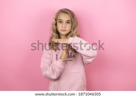 Young beautiful child girl standing over isolated pink background Doing time out gesture with hands, frustrated and serious face