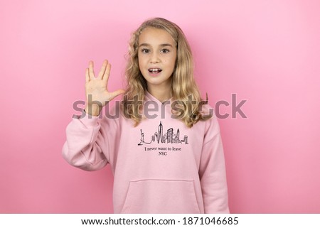 Young beautiful child girl standing over isolated pink background doing hand symbol