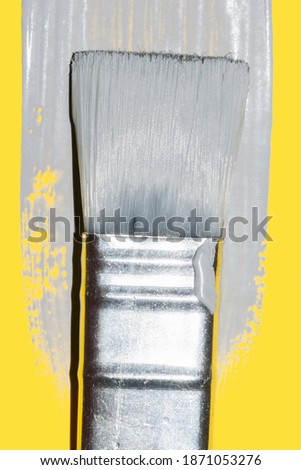 paint brush with fresh ultimate gray paint on illuminating yellow background 2021 color trend
