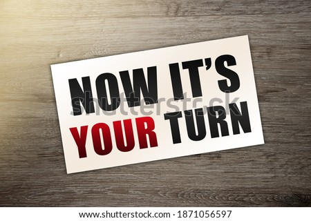 words NOW ITS YOUR TURN in black letters on business card put on wooden table. Business concept.