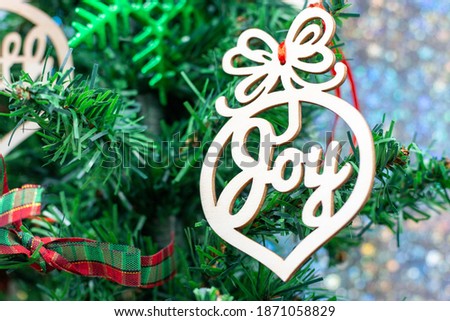 Joy word ornament is hanging on Christmas Tree