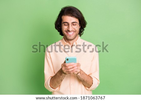 Portrait of attractive focused cheerful guy using device gadget app 5g post smm isolated over bright green color background
