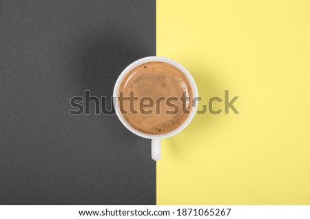 Beautiful white porcelain cup of coffee on double-toned illuminatinf yellow and ultimate gray background. Color trend of the year 2021.
