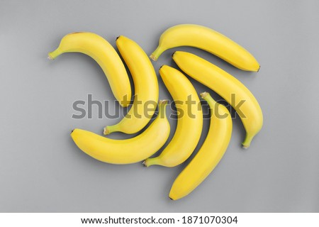 Group of yellow bananas on gray background. Top view, pattern in trendy colors.