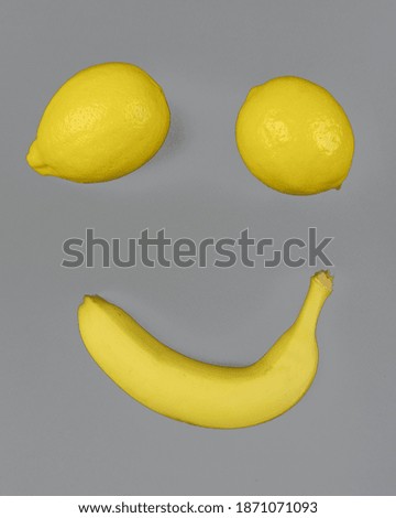 Banana fruit and two lemons on gray background. Smile face.