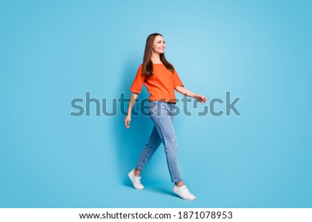 Profile full length photo of attractive shiny lady dressed red t-shirt walking looking empty space isolated blue color background
