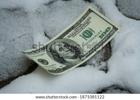 Lost $ 100 banknote on a snowy sidewalk
