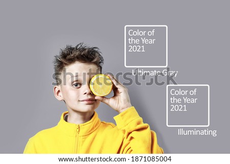 a boy in a bright yellow jacket with a lemon in his hand on a blue background