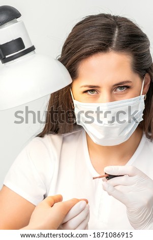 Portrait of manicure master with white protective mask working in a beauty salon