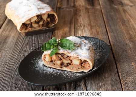 Apple strudel is a delicious puff pastry dessert with apples, nuts and raisins. Strudel is a traditional pastry of Austrian, German, Hungarian and Czech cuisine. Royalty-Free Stock Photo #1871096845