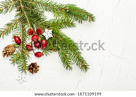 Christmas tree branches with pine cones and rosehip berries on white putty background. New Year greeting card concept, top view