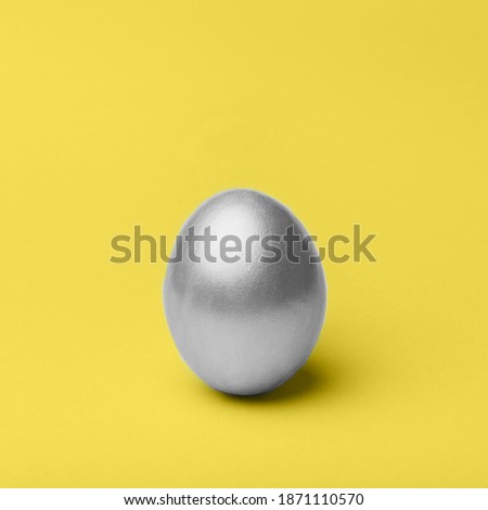 Silver metal easter egg on a yellow background, decoration, holiday background concept. Copy space, wallpaper. Trendy color of 2021 year.