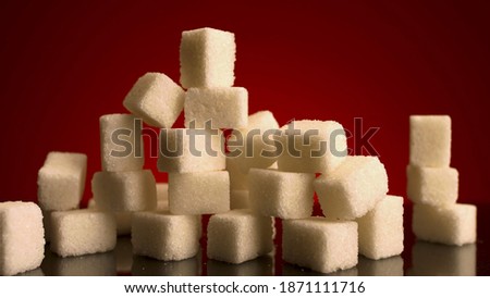 Close up of many sugar cubes standing on the top of each other isolated on red background. Stock footage. Concept of candy, sweets and food. 