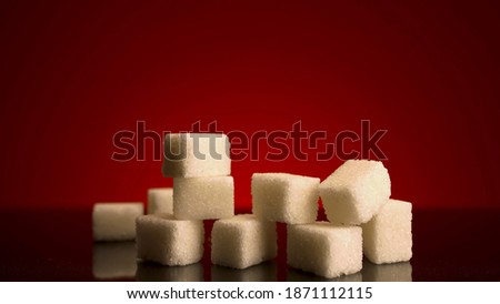 Close up of many sugar cubes standing on the top of each other isolated on red background. Stock footage. Concept of candy, sweets and food. 
