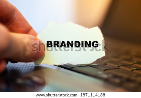 Businessman holds a paper with the word Branding on a computer background.