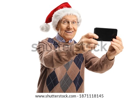 Elderly man with a santa claus hat taking a photo with a mobile phone isolated on white background
