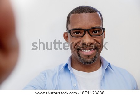 Portrait of young handsome black African man use smartphone selfie say hi over white background. Happy afro guy online influencer blogger. Education technology connected people man lifestyle concept