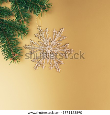 Golden snowflake with a spruce branches on a golden background. Christmas wallpaper or postcard concept. Flat lay. Place for text.
