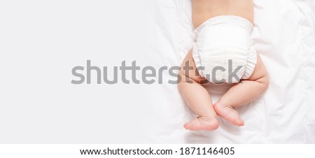 Cute caucasian infant baby in white nappy on light grey blanket. Top view. Banner format. Copy space. Diaper change and care of baby's skin.  Royalty-Free Stock Photo #1871146405