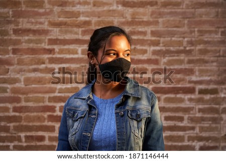 Portrait of an African American black woman wearing face mask outdoors. New normal in times of coronavirus due to the covid19 pandemic. Royalty-Free Stock Photo #1871146444