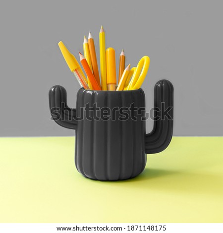 Orange yellow stationery in cactus glass on gray and yellow. Hipster minimal concept. Front view. Color 2021.