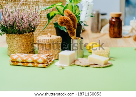 Set of eco friendly natural cleaning products, bamboo brush, lemon, baking soda, spray bottle, wicker basket, kitchen towels, glass bottle on green background. Zero waste lifestyle concept.