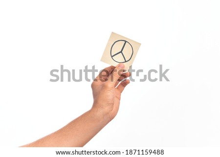Hand of caucasian young man holding reminder paper with peace symbol over isolated white background