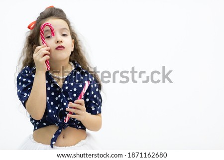 View of a little girl holding two lollipops.