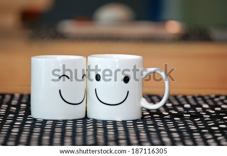 Two happy cups on wood table with black polka dot tablecloth. Concept about love and relationship                     Royalty-Free Stock Photo #187116305