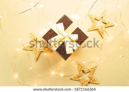 Christmas gift box with festive ribbons, golden stars and blurred lights